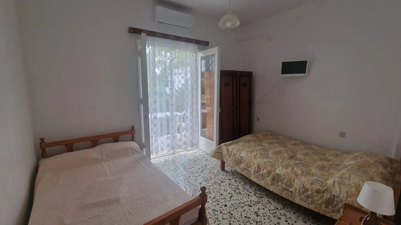 Spavaća soba Apartmana 1 sa dva kreveta, ormarom, klima uređajem i vratima
                    ka balkonu