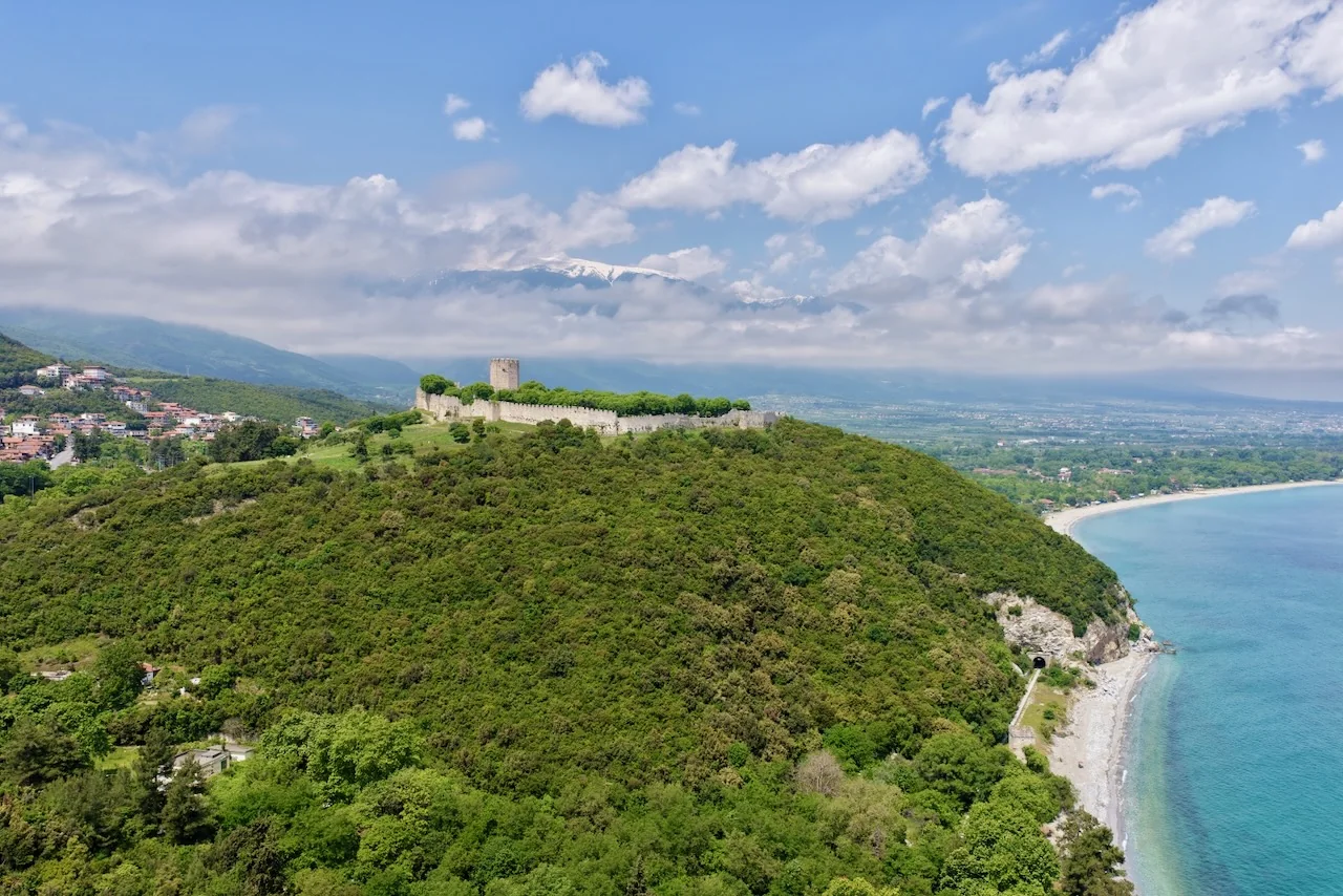 Byzantinische Burg von Platamonas auf dem bewaldeten Hügel über der Küste, im Hintergrund der schneebedeckte Olymp