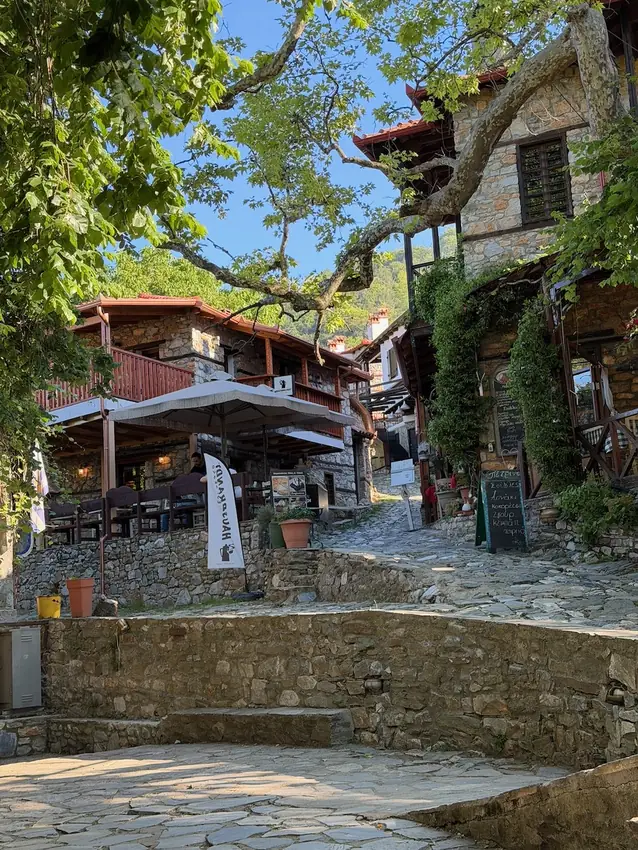 Lane in Palaios Panteleimonas with traditional stone houses, balconies and small
                    tavernas